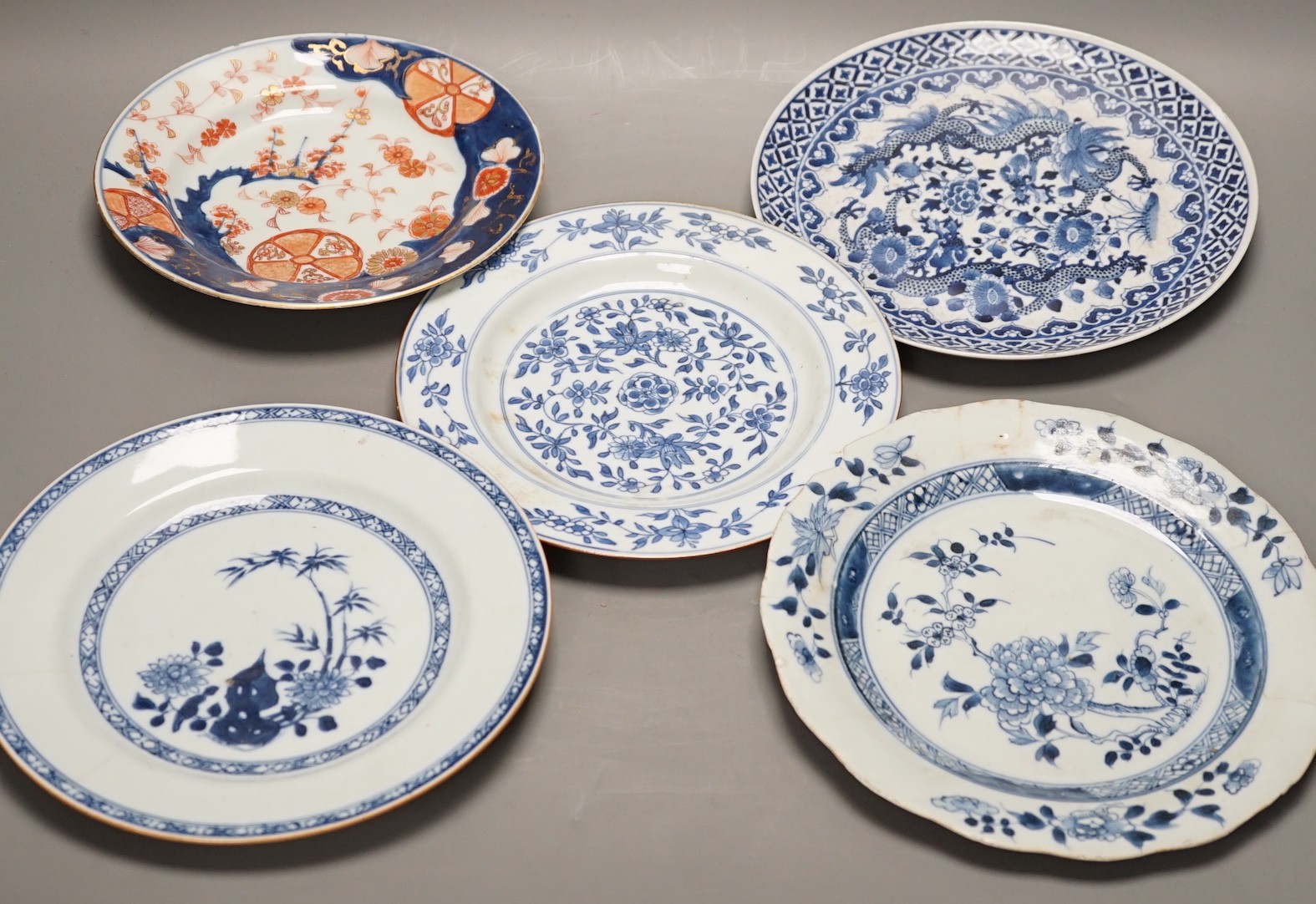 Four Chinese 18th century plates and a late 19th century blue and white dragon plate, largest 24cm diameter